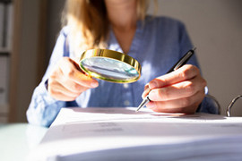 Image of Woman using magnifying glass to investigate.